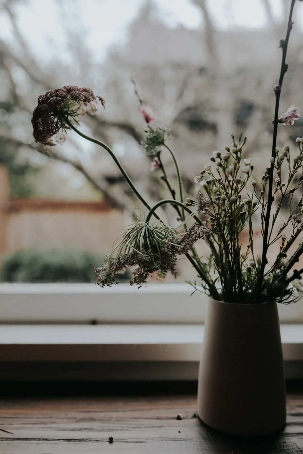 Bouquet of wildflowers in a vase on a wooden table by window