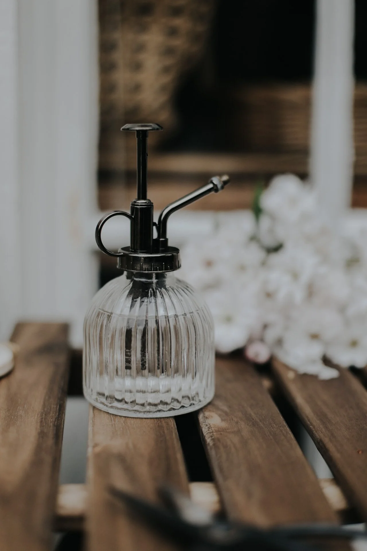 Glass plant mister on wooden surface with blurred background
