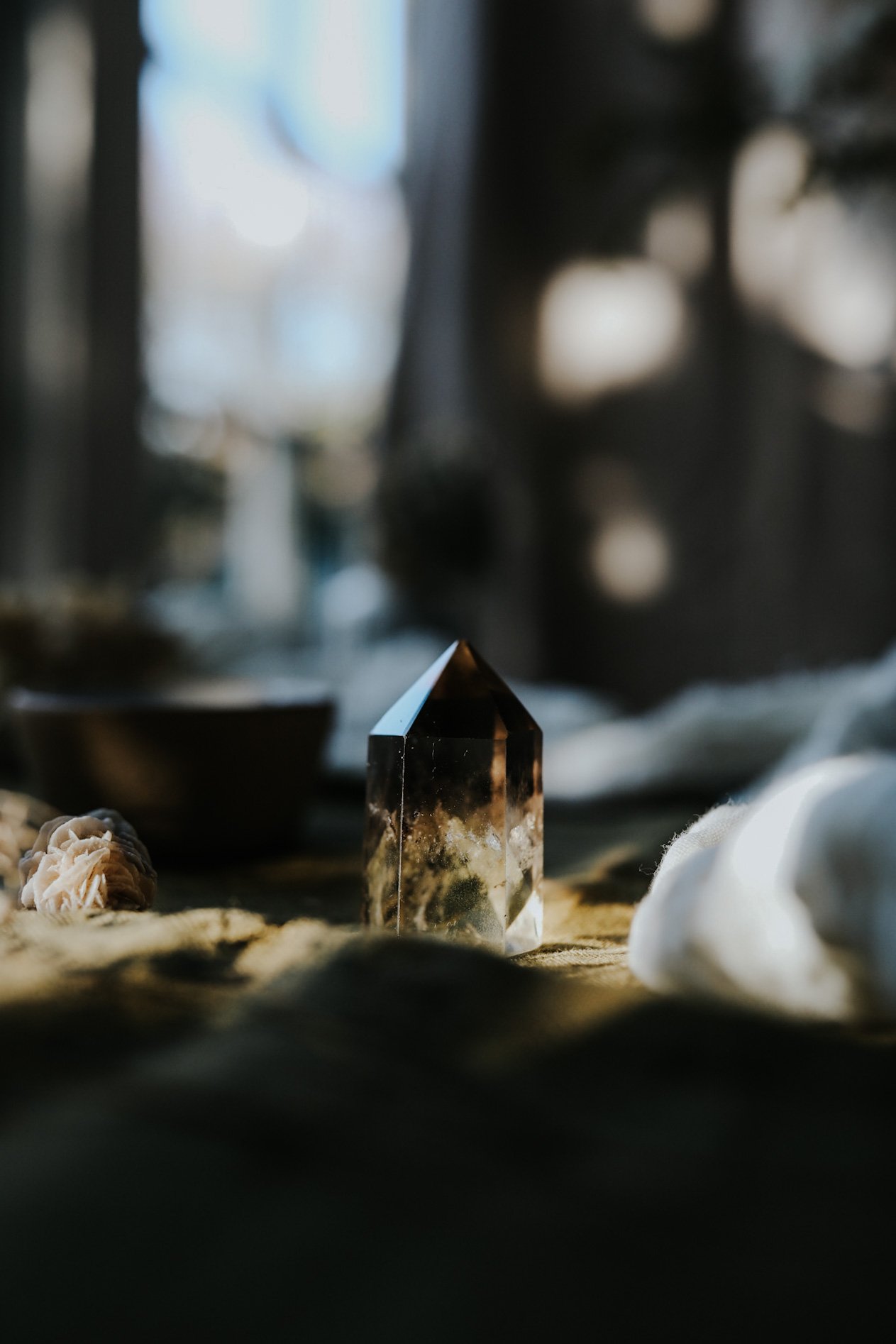 Smoky quartz crystal point on a soft cloth surface with blurred background.