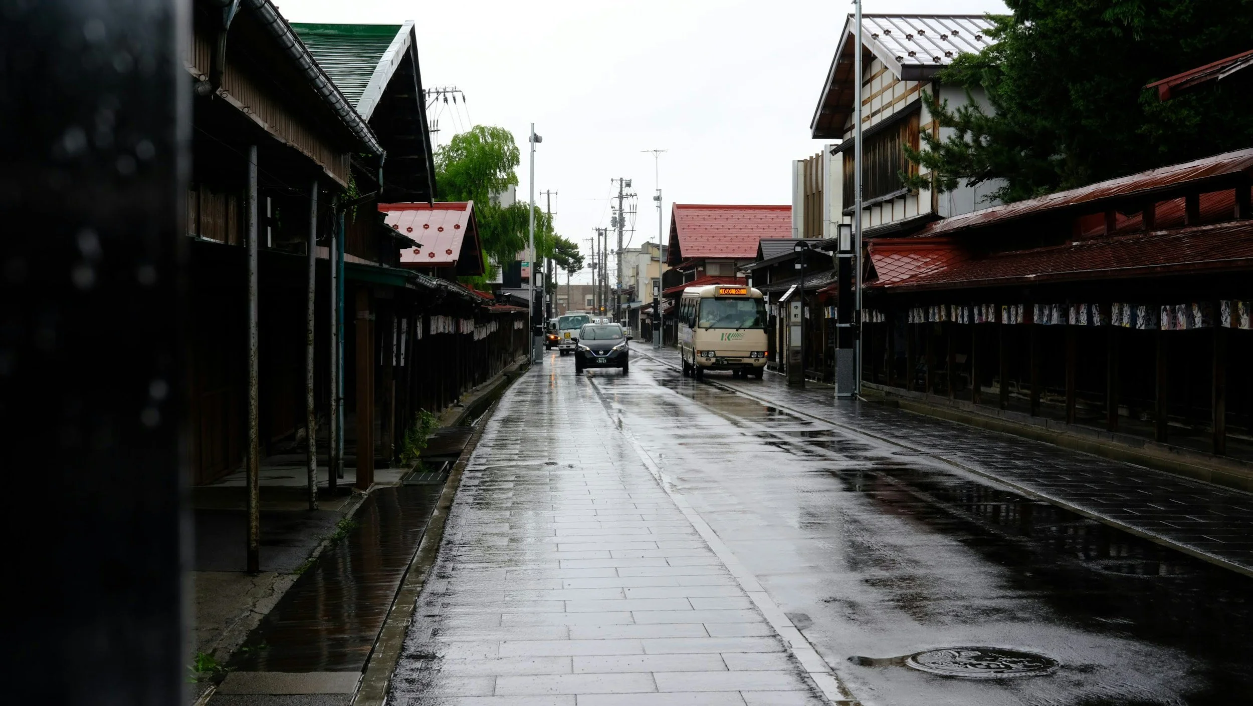 Rainy side street with cars and buses