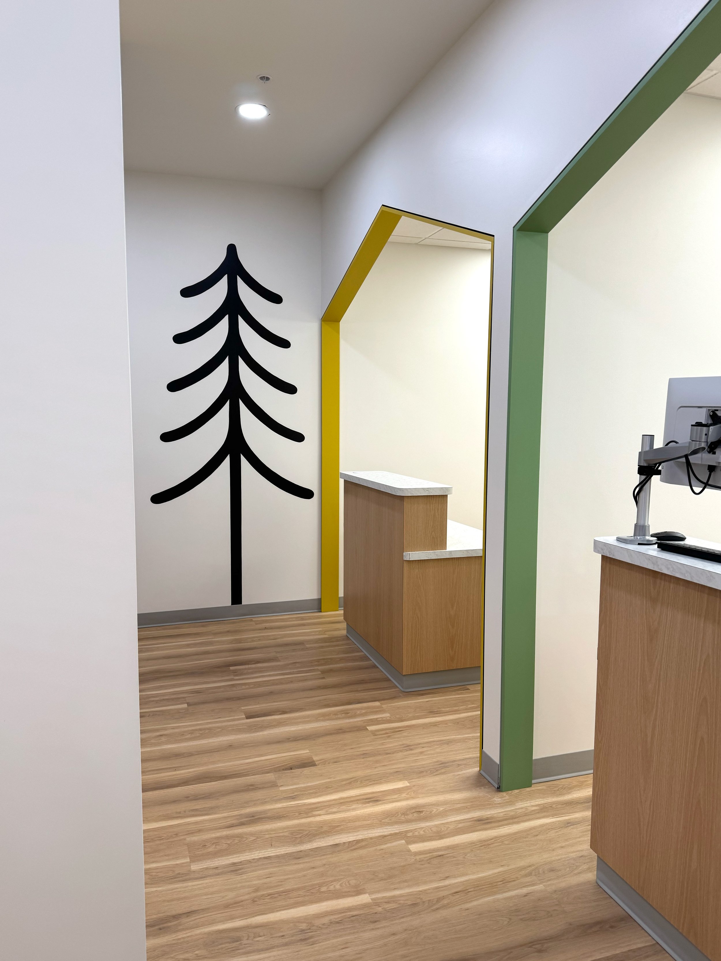 Colorful mural with images of a plane, globe, evergreen trees, eagle, orca whale, flower, beaver, moose, and a yellow striped pattern.