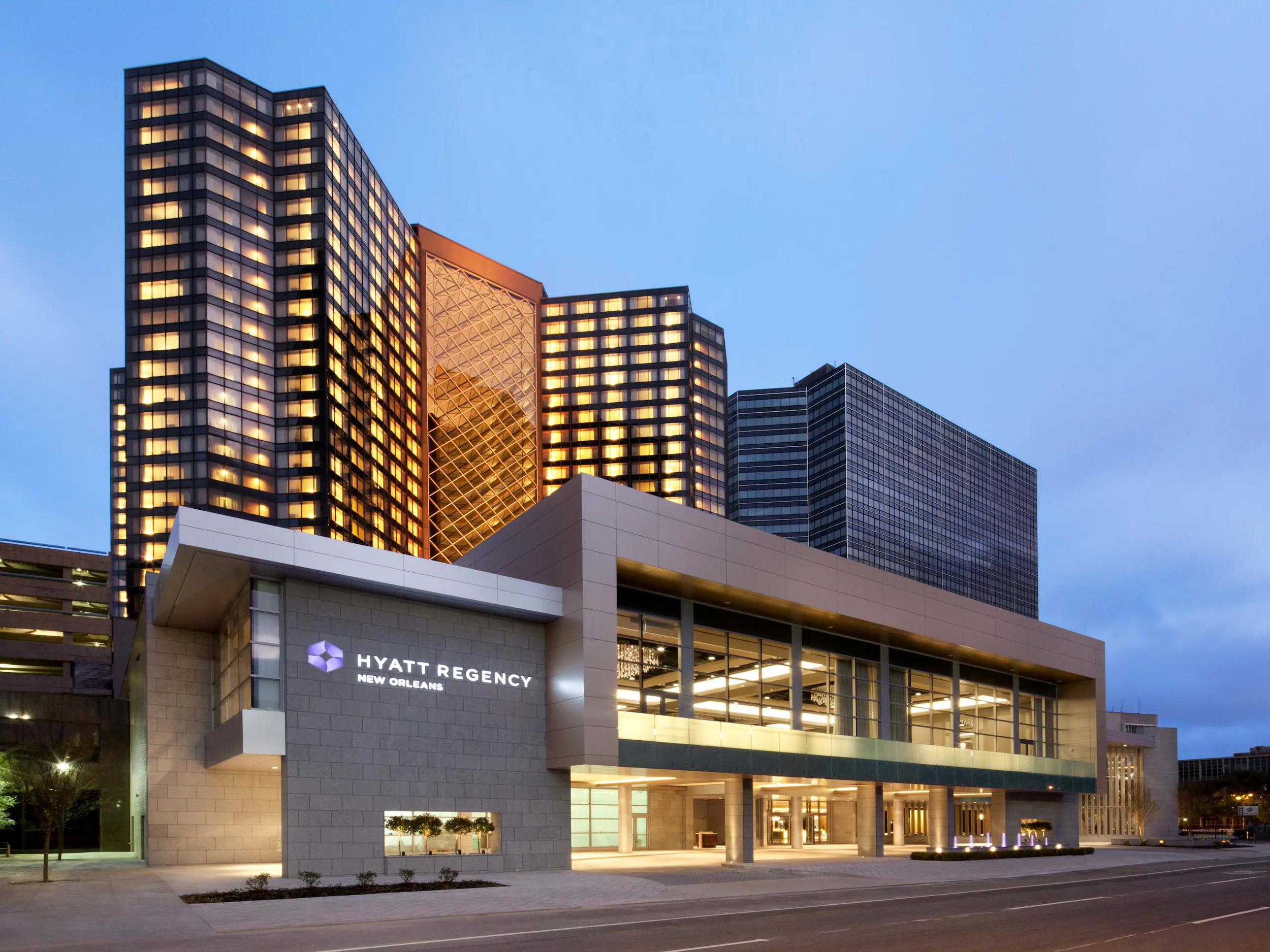 Hyatt Regency New Orleans hotel exterior at dusk, featuring modern glass towers and the main entrance, location of the Curate Completely Unconfused Conference in New Orleans, Louisiana.