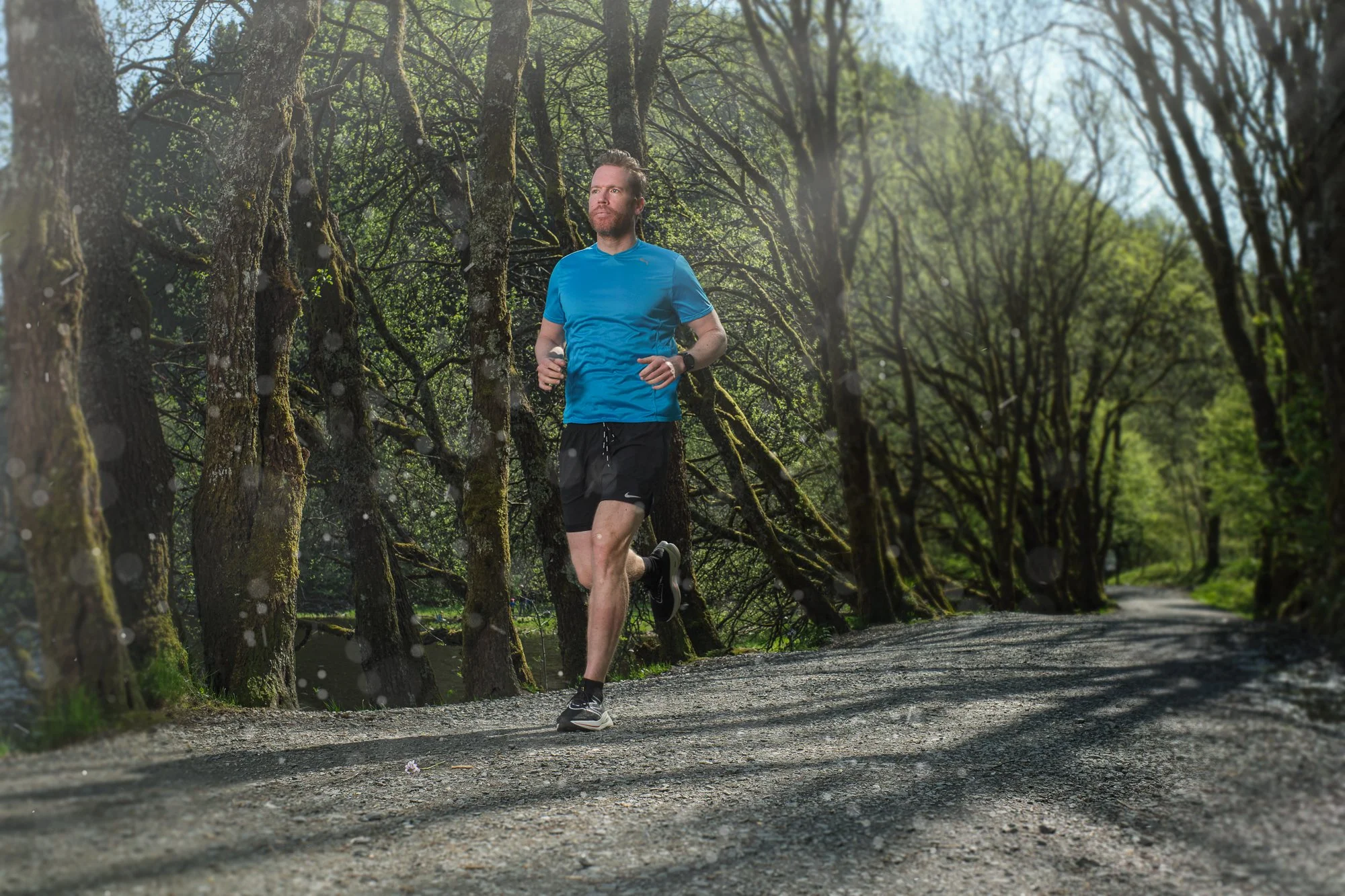 En mann jogger på en skogssti i grønne omgivelser.