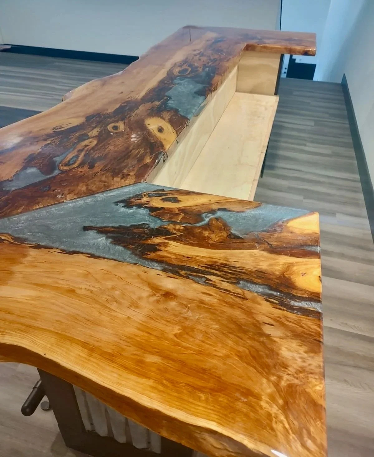 Bar top made from a live edge slab with resin inlay and a metal base inside a home game room.