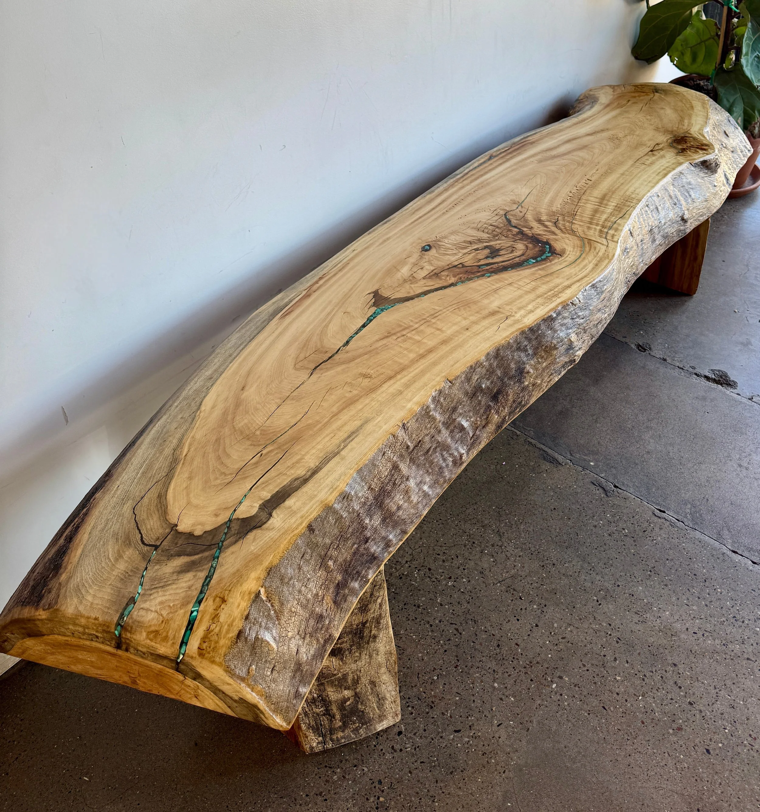 Rustic live-edge wood bench with beautiful wood grain and turquoise inlay.