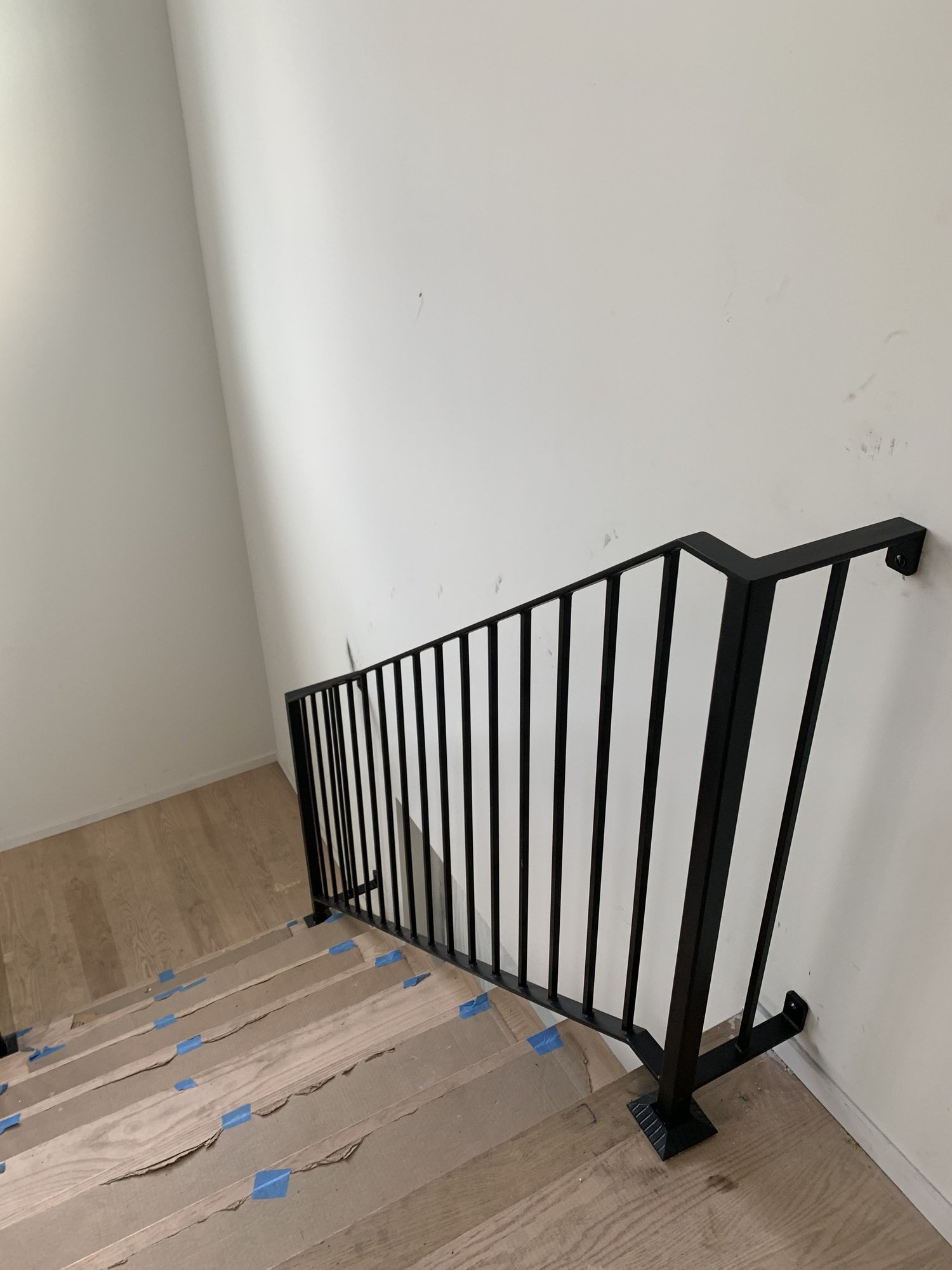 Black flat bar stair railing installed on a new wood staircase
