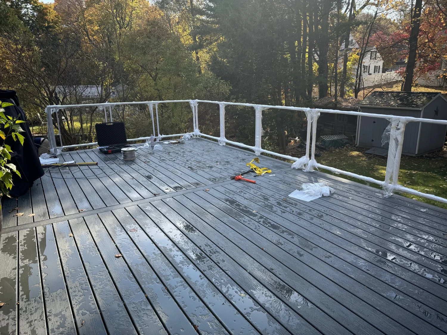 Deck and stair railing sections going in on a gray wood deck