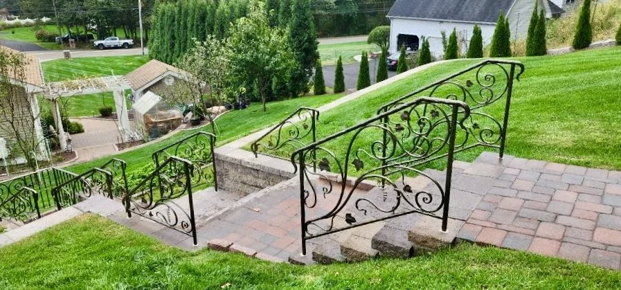 Ornamental handrails on brick and stone steps down a landscaped hillside