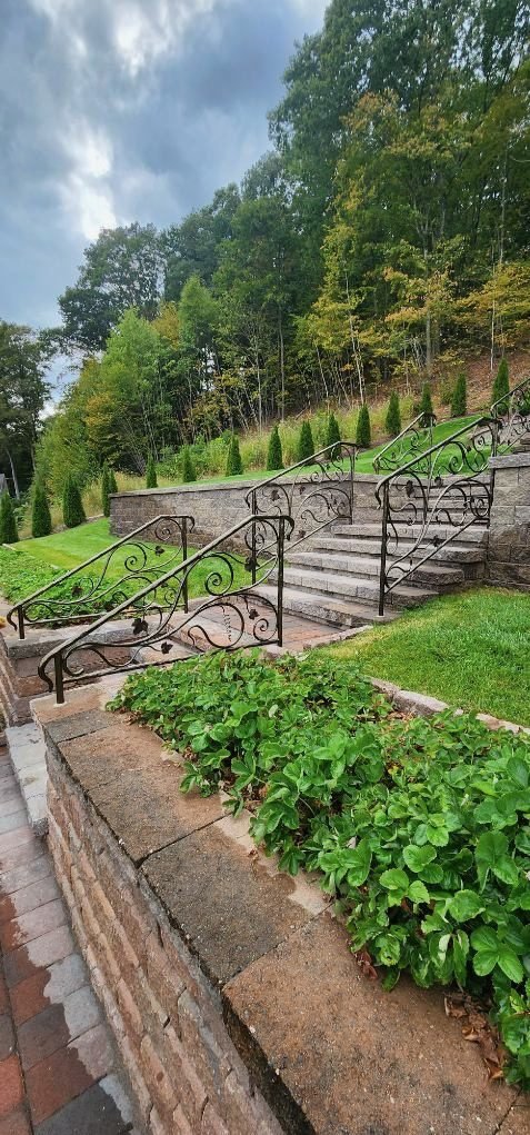 Black metal railing following terraced stone garden steps beside a retaining wall