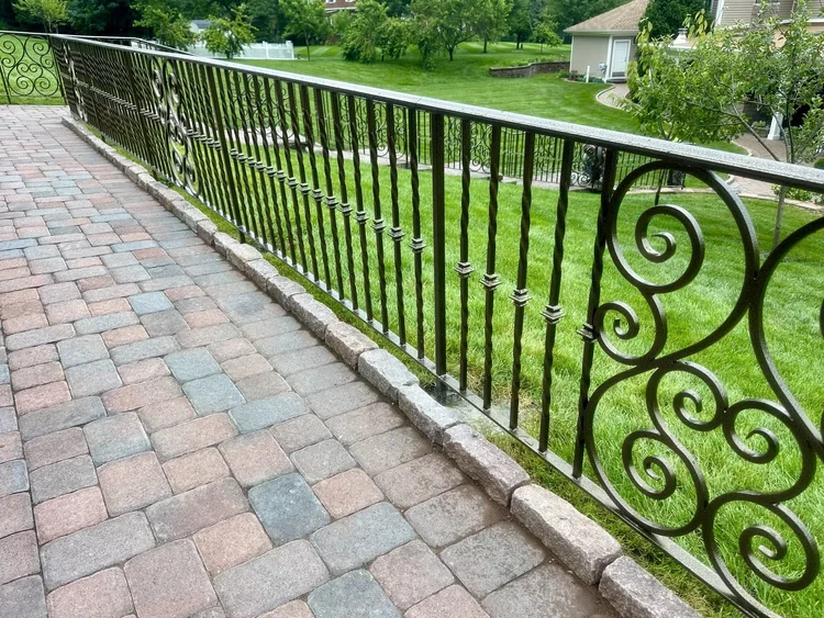 Close-up of twisted balusters and a scroll panel on a black wrought iron railing