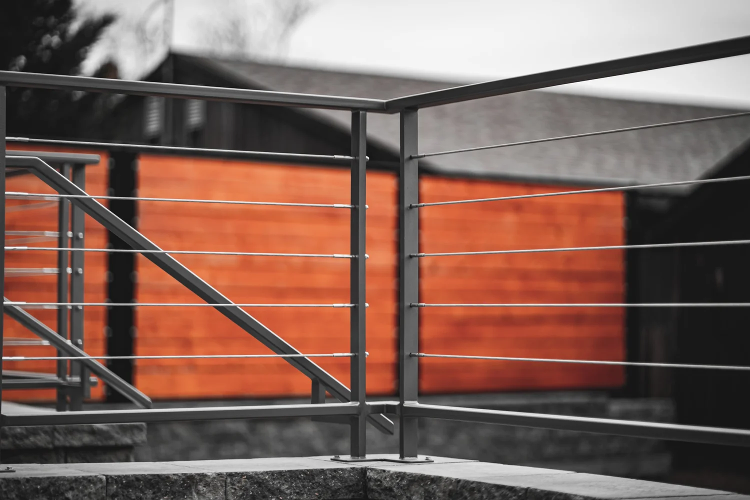 Metal cable railing in front of a stained wood wall