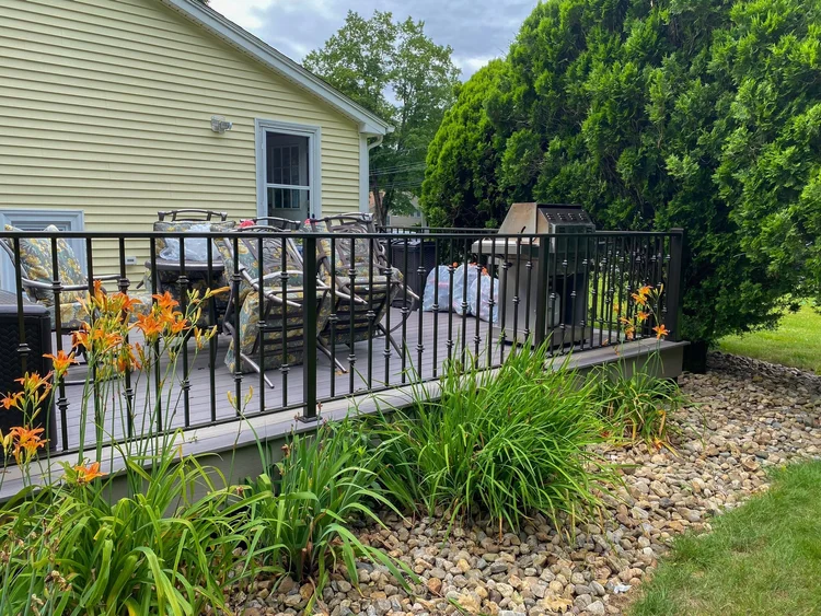 Black metal deck railing with decorative collars around a backyard deck