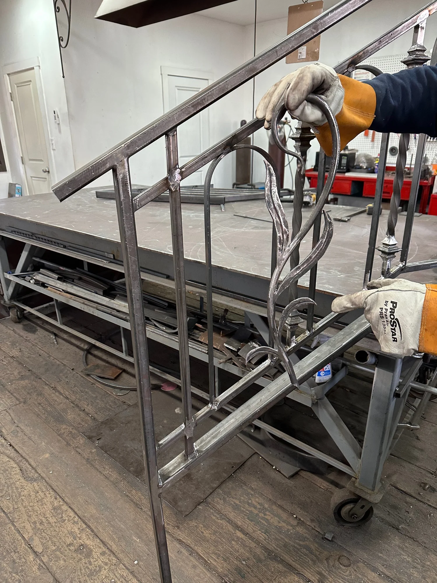 Metalworker holding a steel railing section on the fabrication table