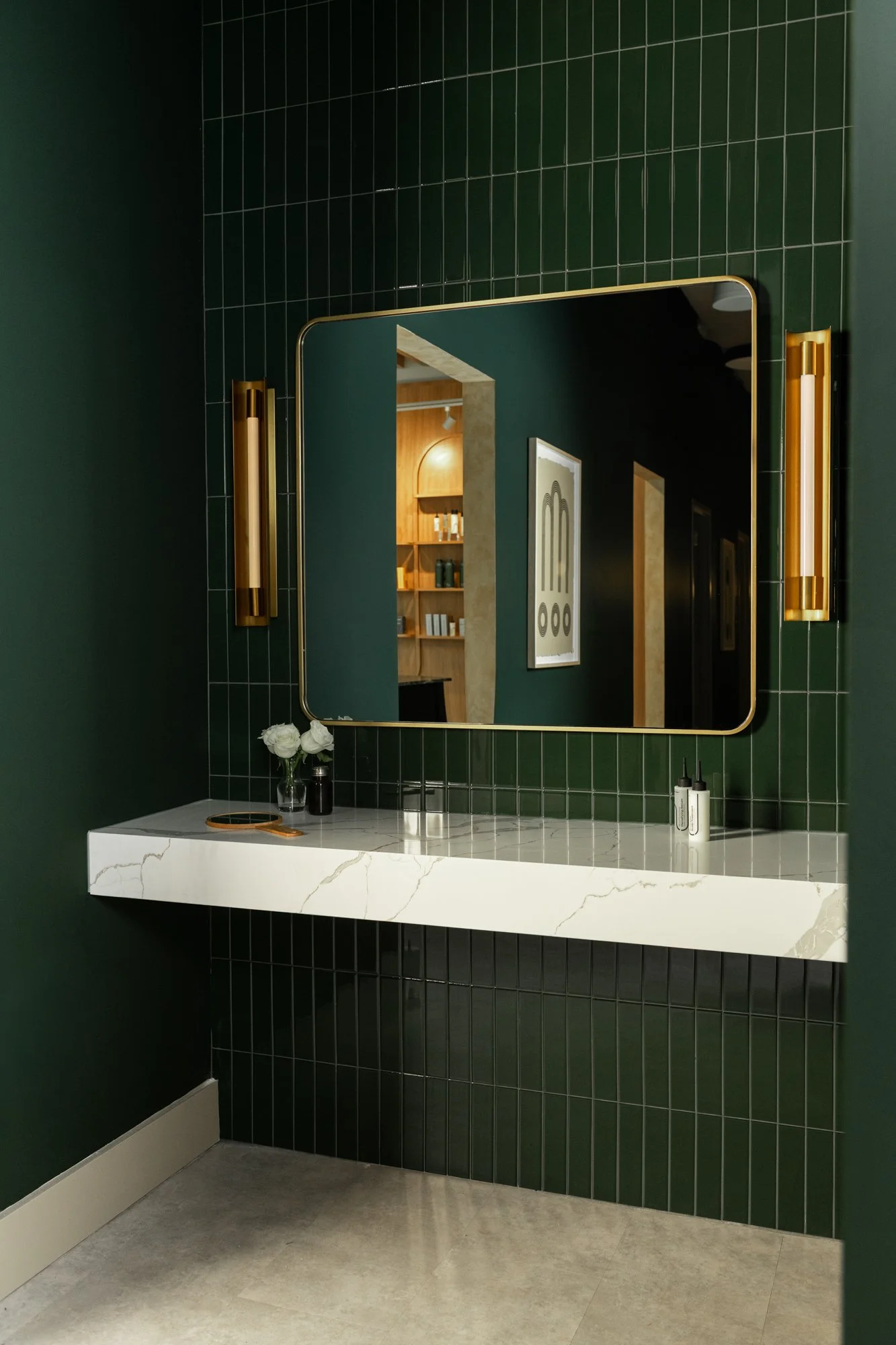 Vanity area at Great Many's Washington DC studio with deep green subway tile and brass accents