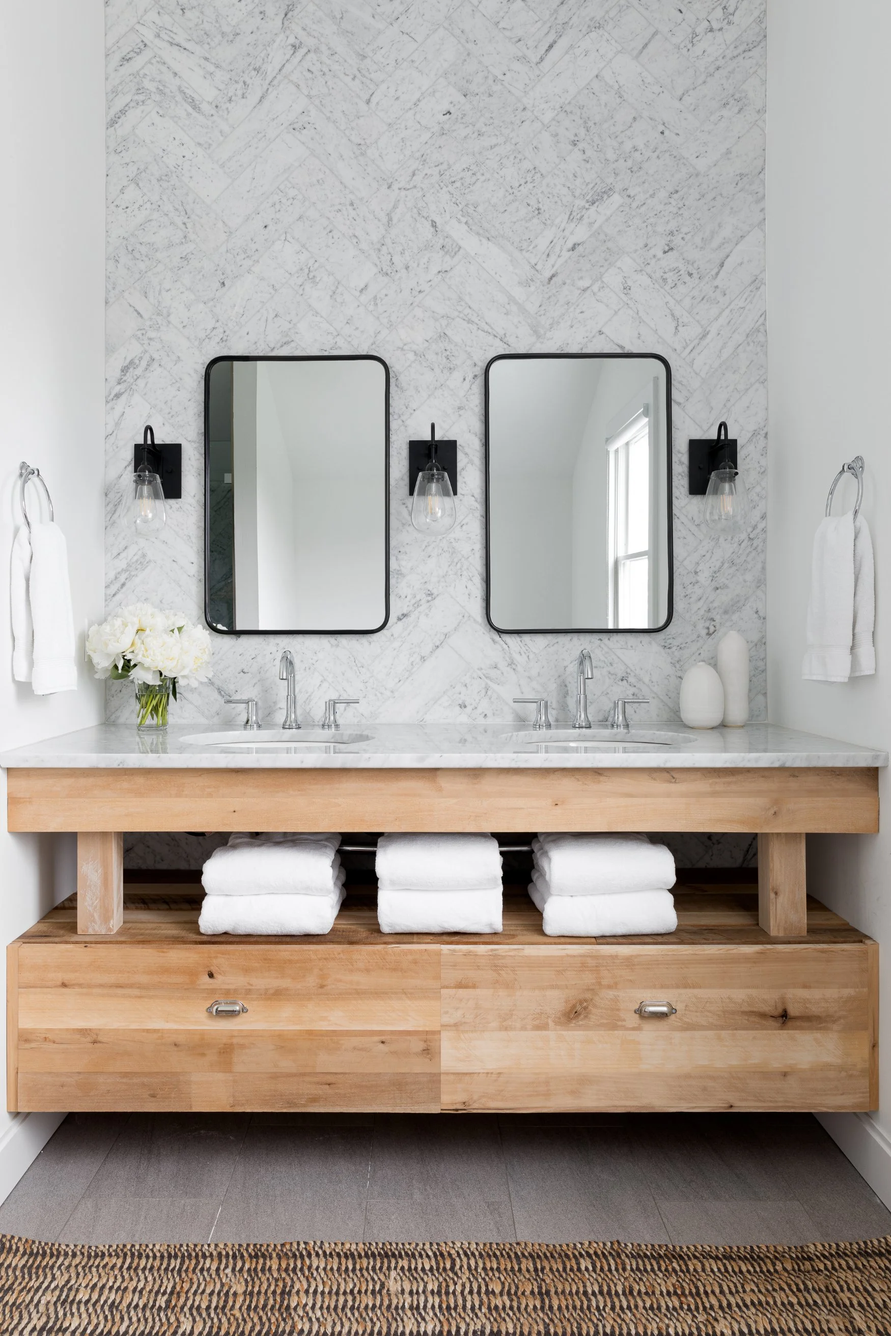 Bathroom with double sinks, wood cabinets, textured wall, and rectangle mirrors