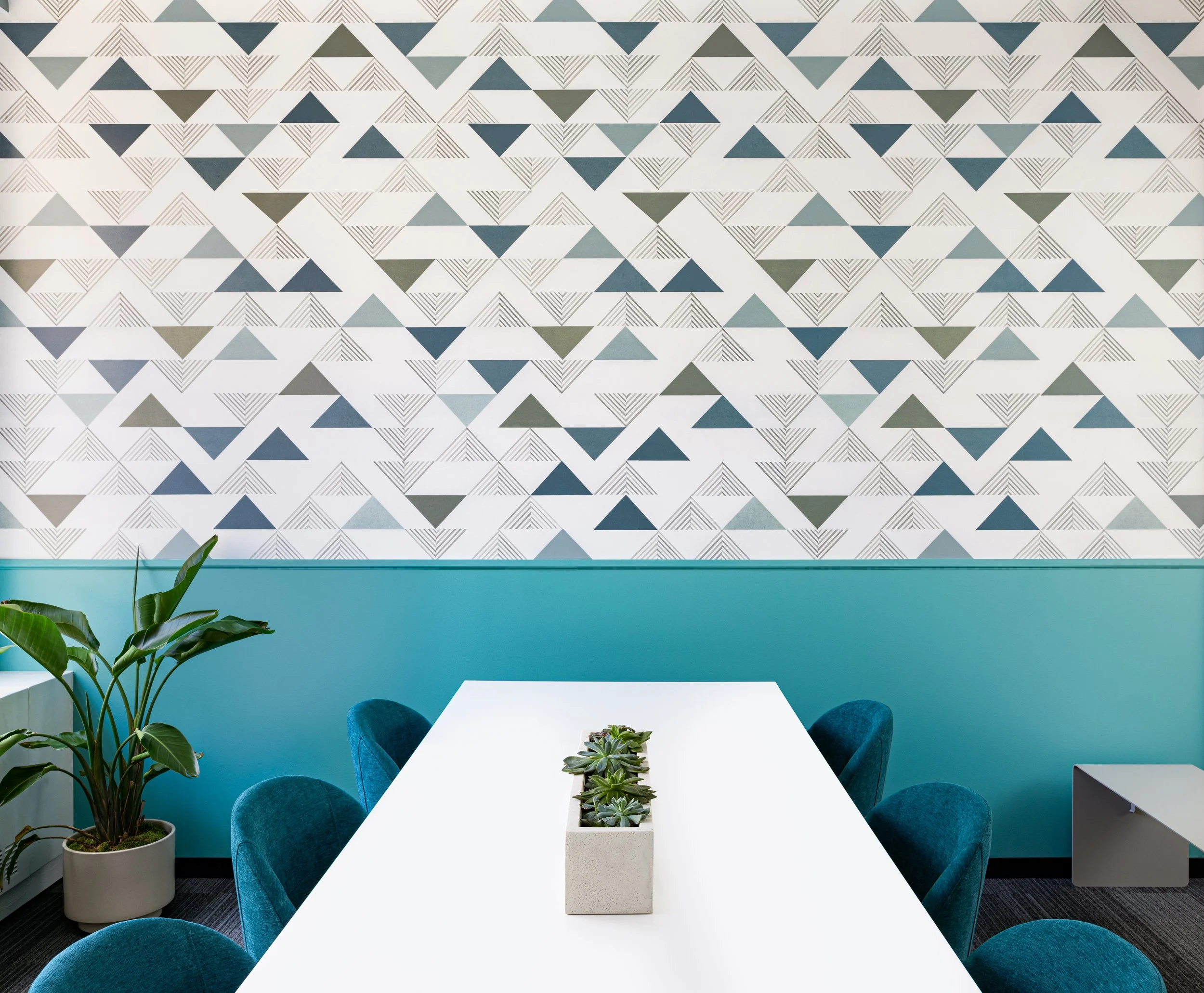 Conference room with triangle wallpaper, long white table, and blue chairs