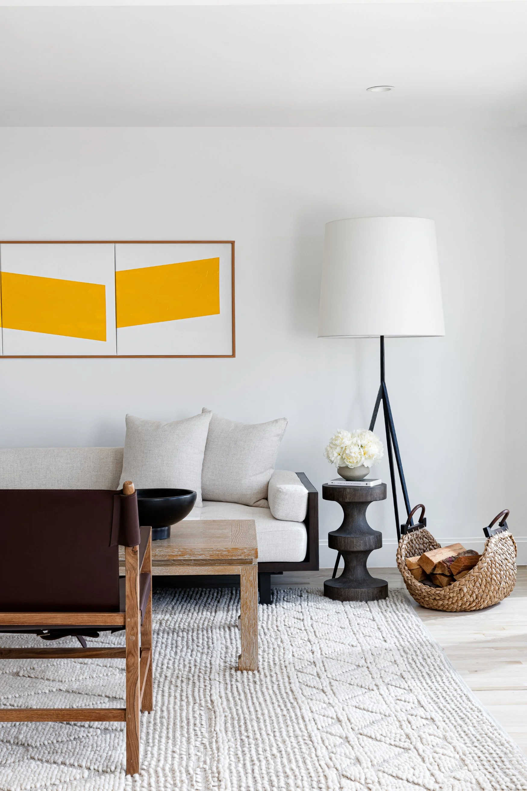 Living room with textured cream area rug, gray bench, white couch, black chairs, and wood coffee table
