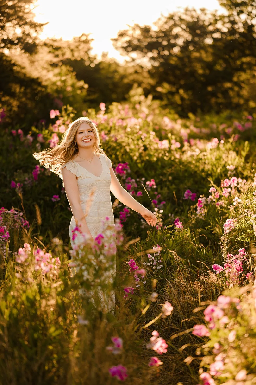 Best Seattle senior photos, blonde girl in a white dress twirling in a field of pink wildflowers in the sunshine