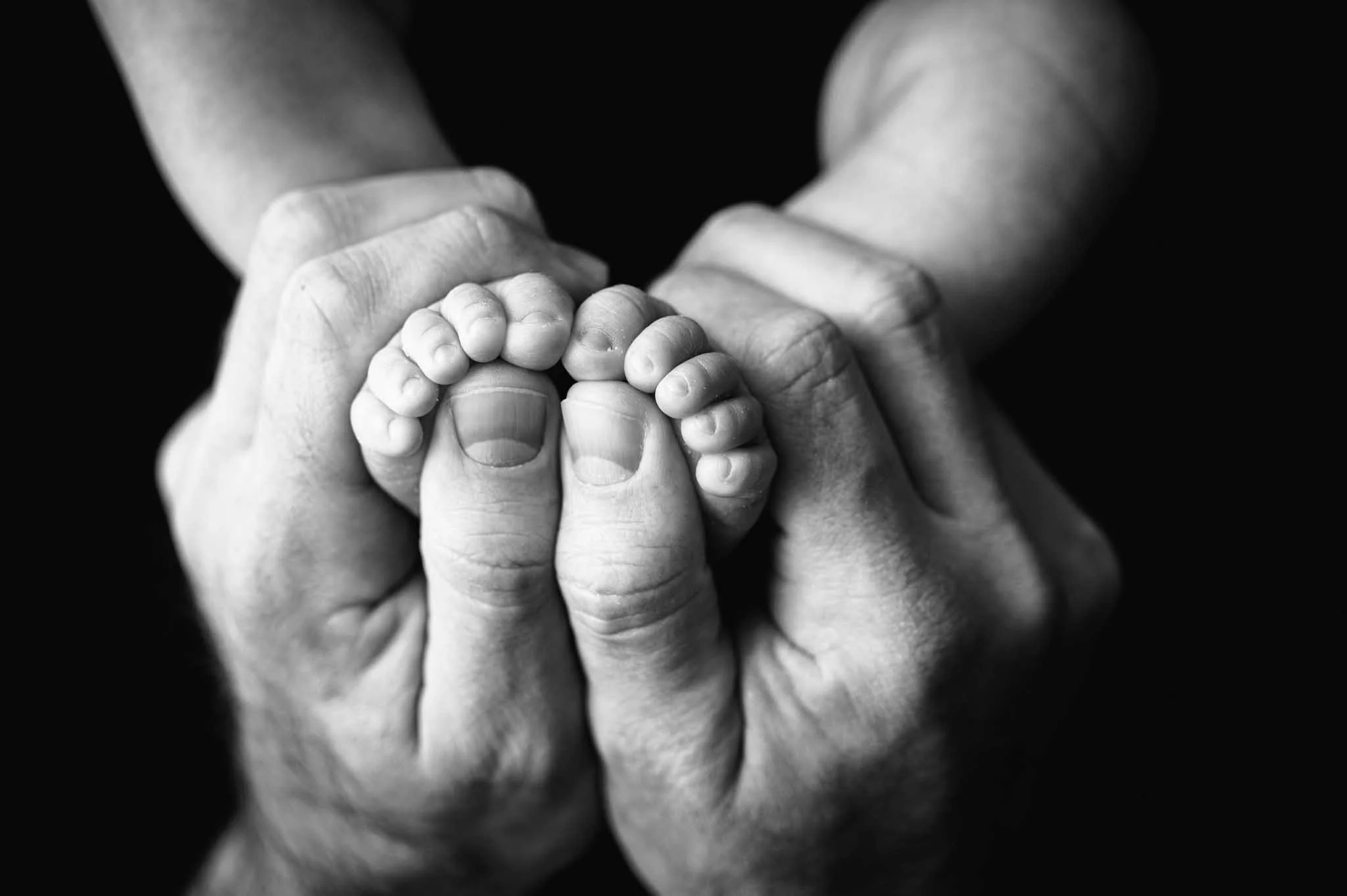 Dad holding newborn feet showcasing tiny toes