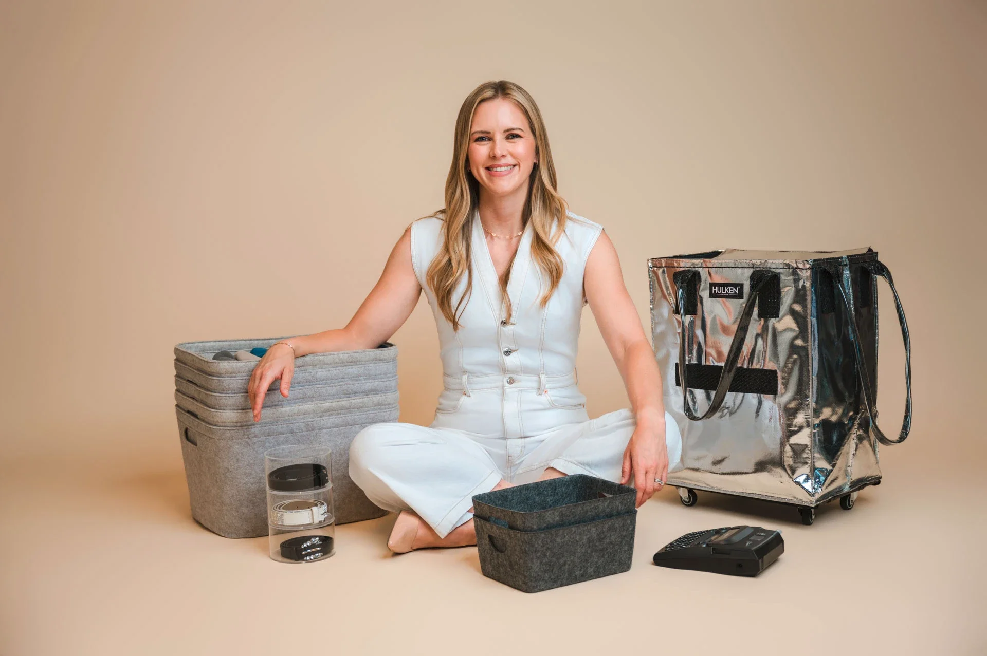 Woman in white seated beside product displays during a studio branding photo shoot.
