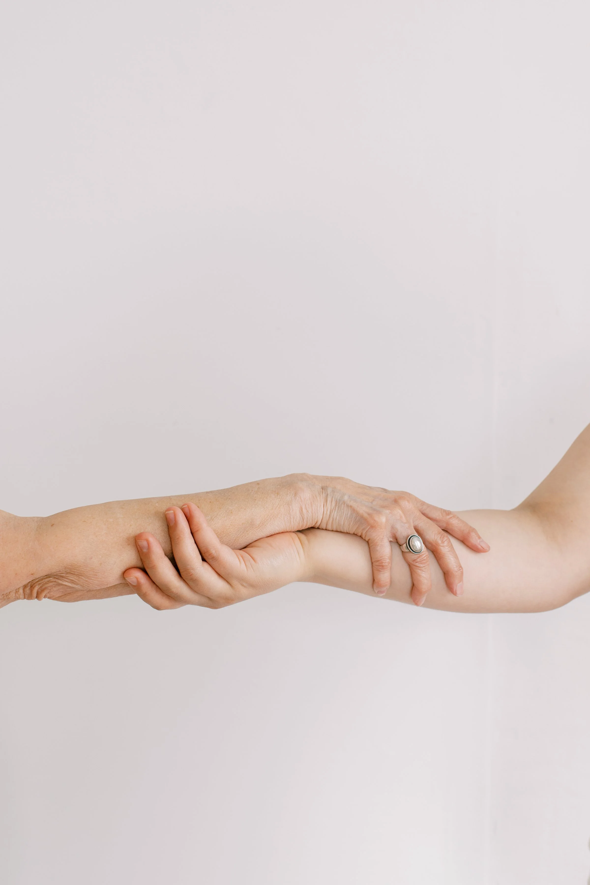 Two hands holding each other's forearms against a plain white background.