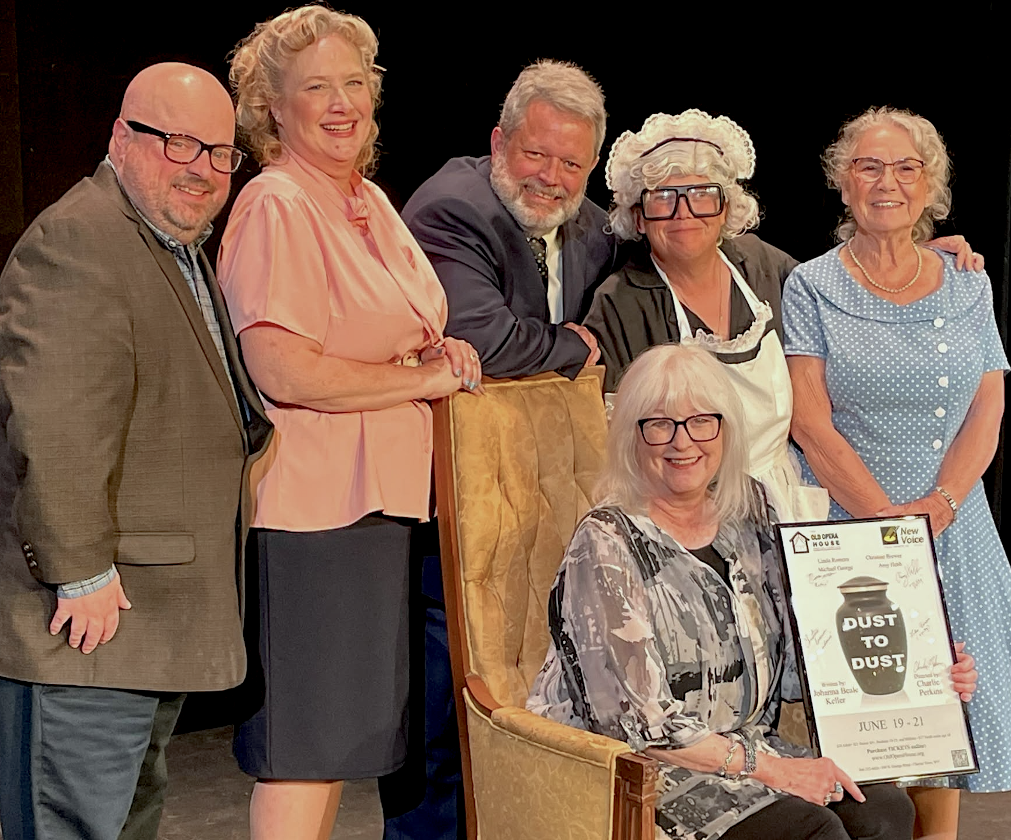 People standing together at an event, with some holding a framed poster and smiling at the camera.