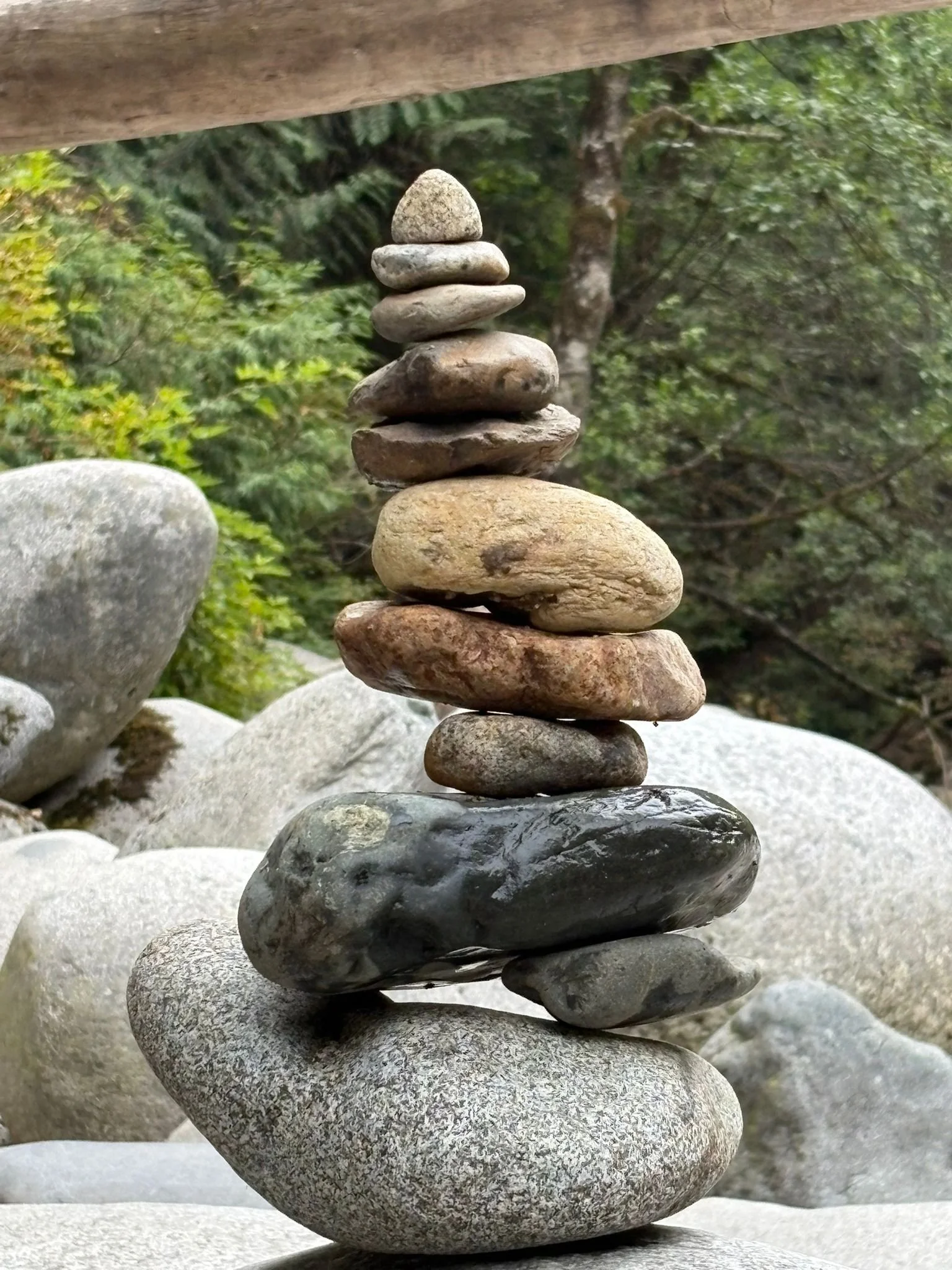 Stacked stones in a balancing formation outdoors with trees and rocks in the background.