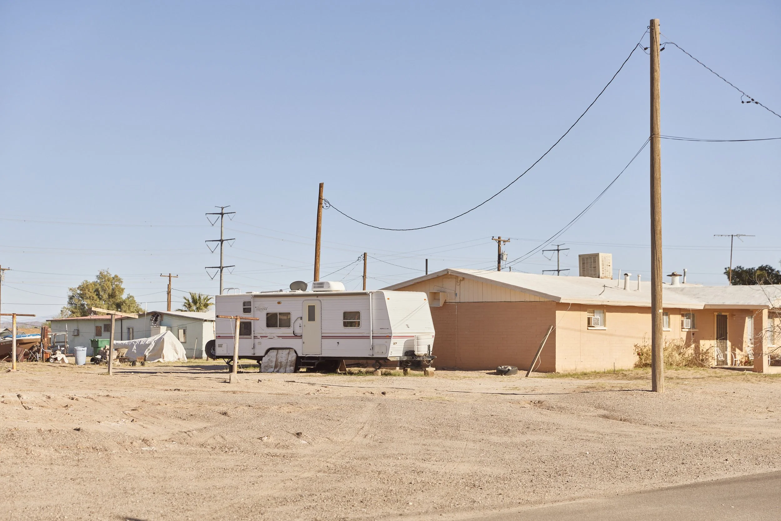 Residential dirt lot with mobile trailer, small home, and utility poles in Randolph, Arizona — reportage-style image by Matt Martian, Phoenix-based photographer