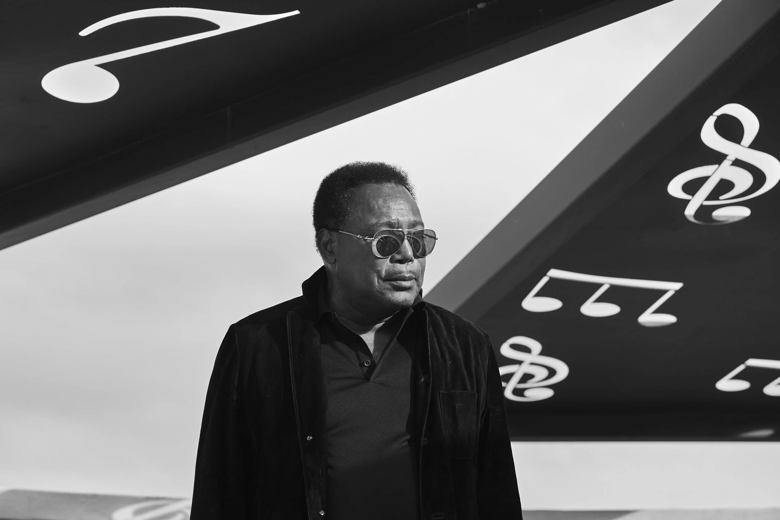 Person wearing sunglasses under a structure with musical notes.