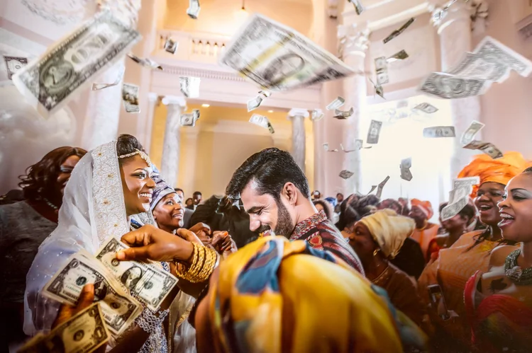 People celebrating at a wedding, throwing dollar bills in the air.