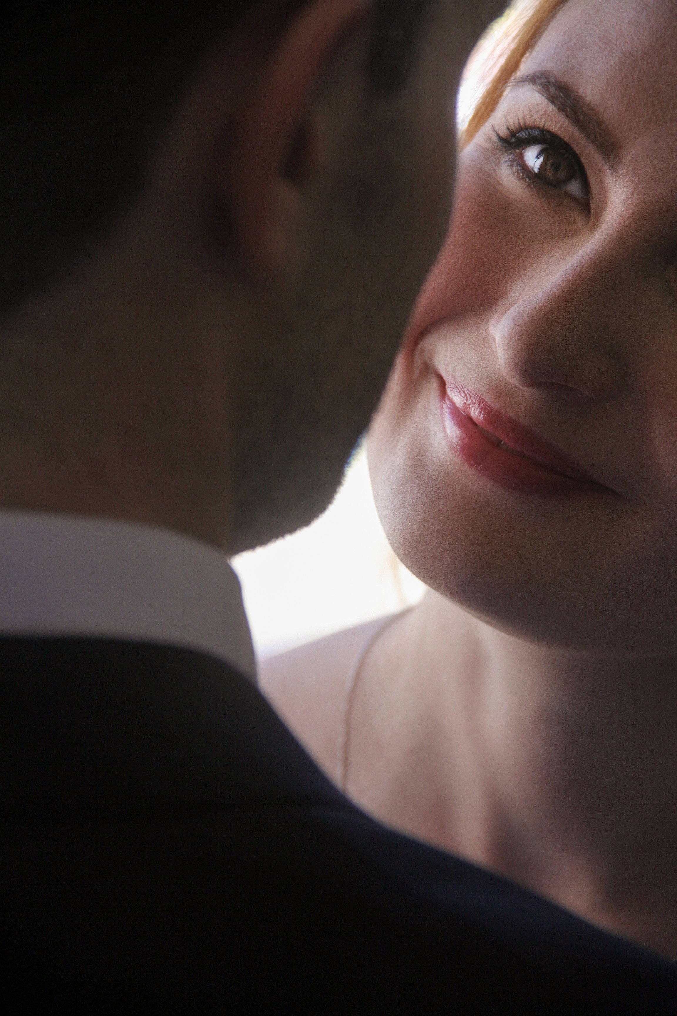 Close-up of a woman smiling at a man, with only part of the man's face visible.
