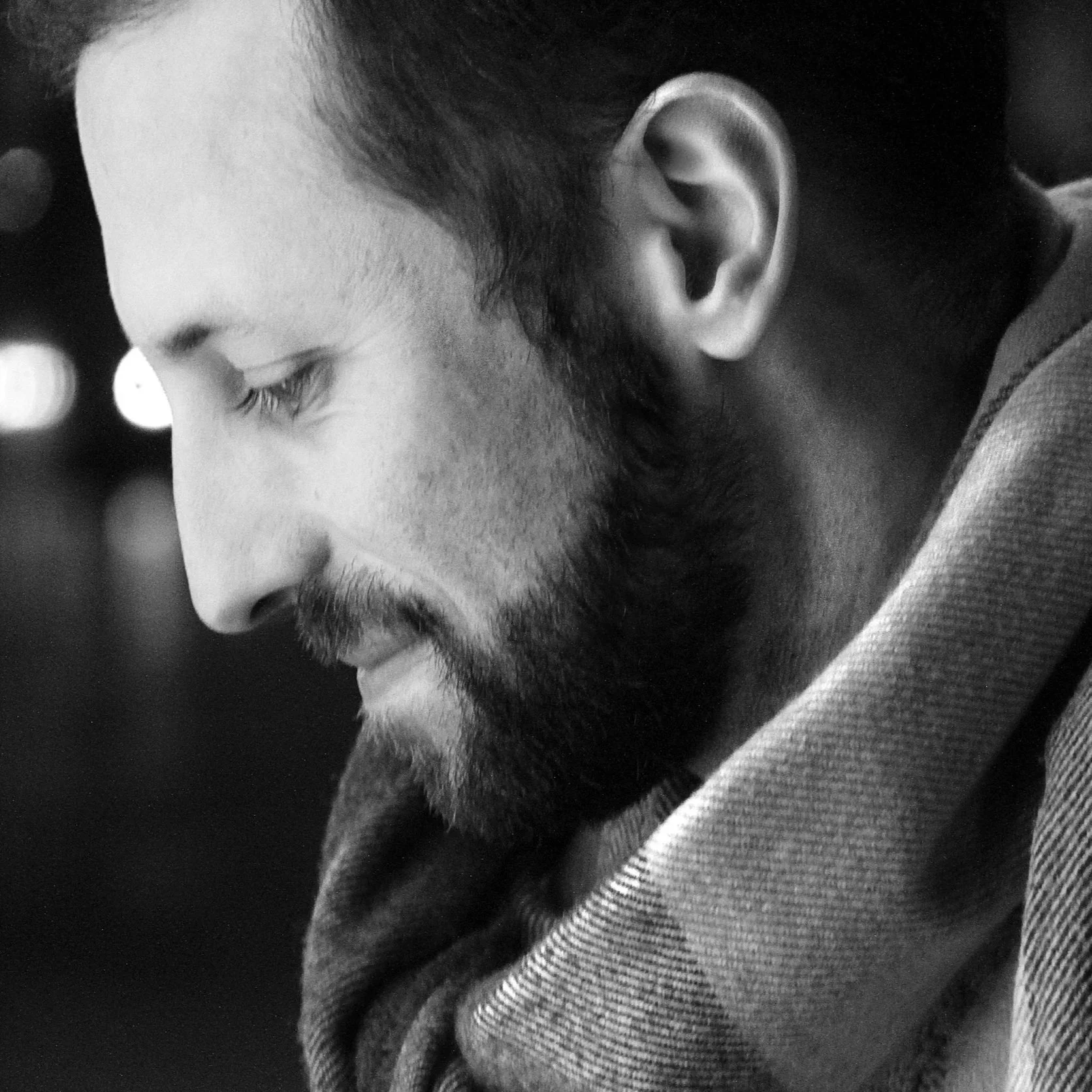 A close-up black and white photograph of a man with a beard and closed eyes, showing his side profile.