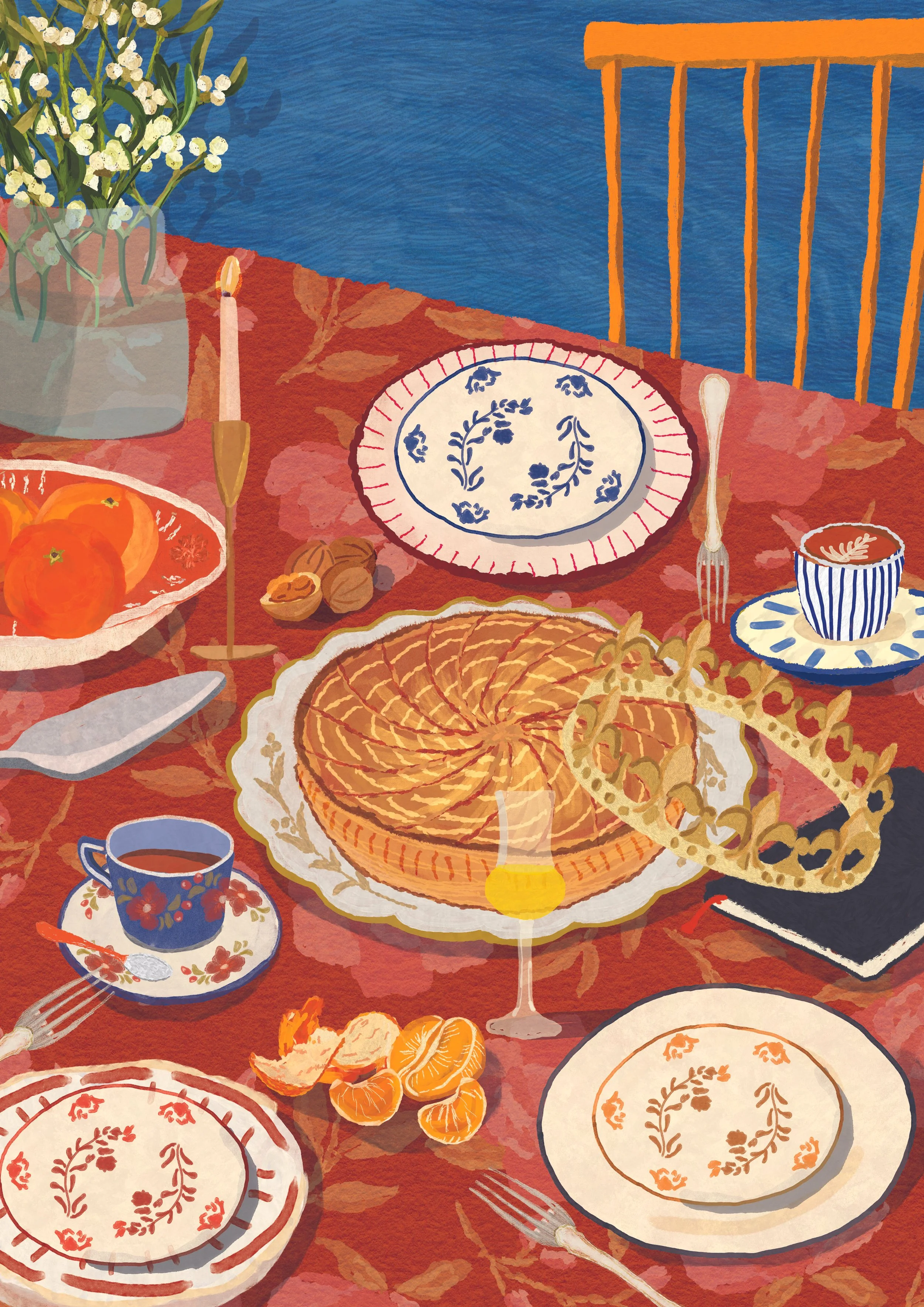 Table pour fêter la Galette, des assiettes décoratives, une tasse de thé, une tasse de café, une clementine, des noix, une bougie, un vase de fleurs, une couronne en or et des assiettes vides avec des motifs floraux.