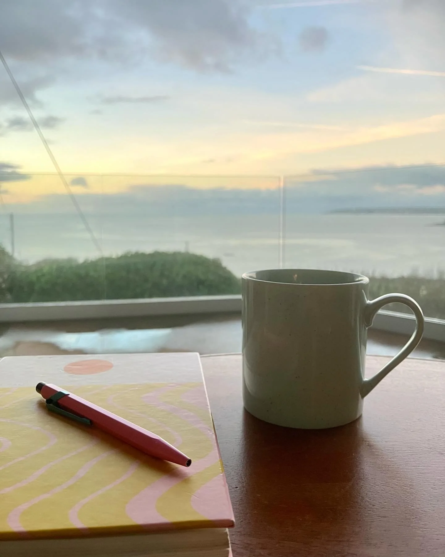 My ritual last week on retreat was to get up at 6am, settle in an armchair with my notebook and laptop, and watch the light slowly turn from the flicker of electrics across the bay to sunrise. Mostly the colours were subdued by clouds but one morning