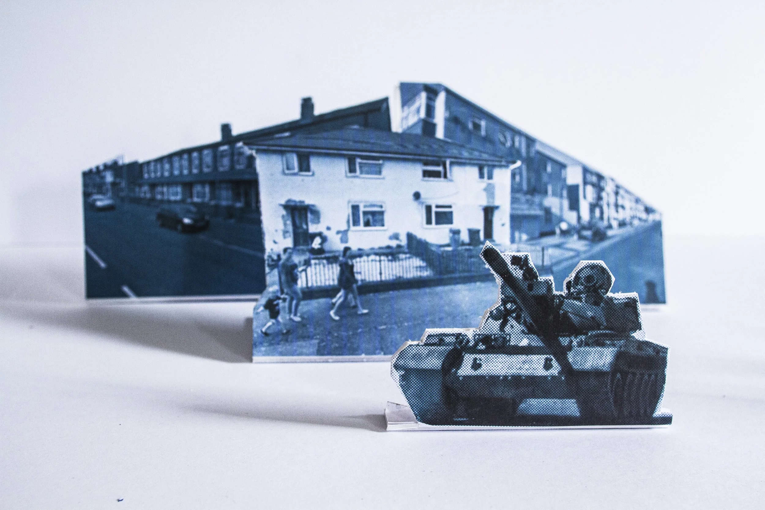 A collage of black and white photographs featuring a building, children playing, and a small sculpture on a white background.