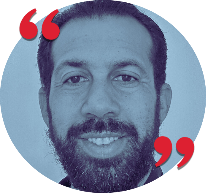 Portrait of a man with dark hair and a beard smiling at the camera.