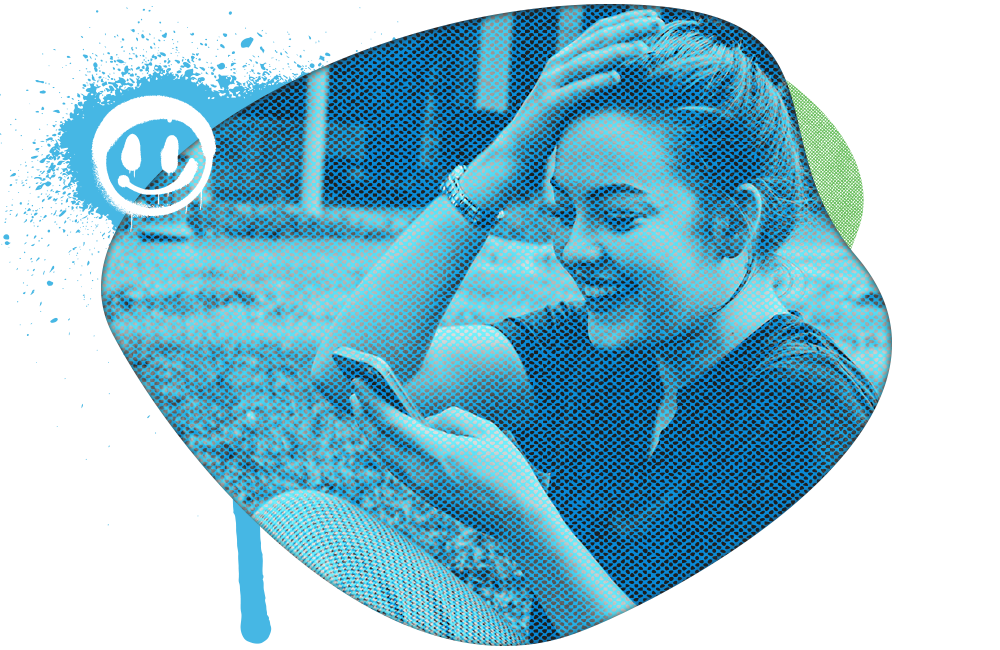 Woman smiling at her phone, sitting outdoors