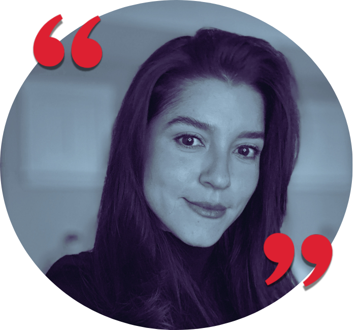 A woman with long purple hair smiling at the camera, with a blurred background. The image has a blue tint and red quotation marks in the upper left and lower right corners.