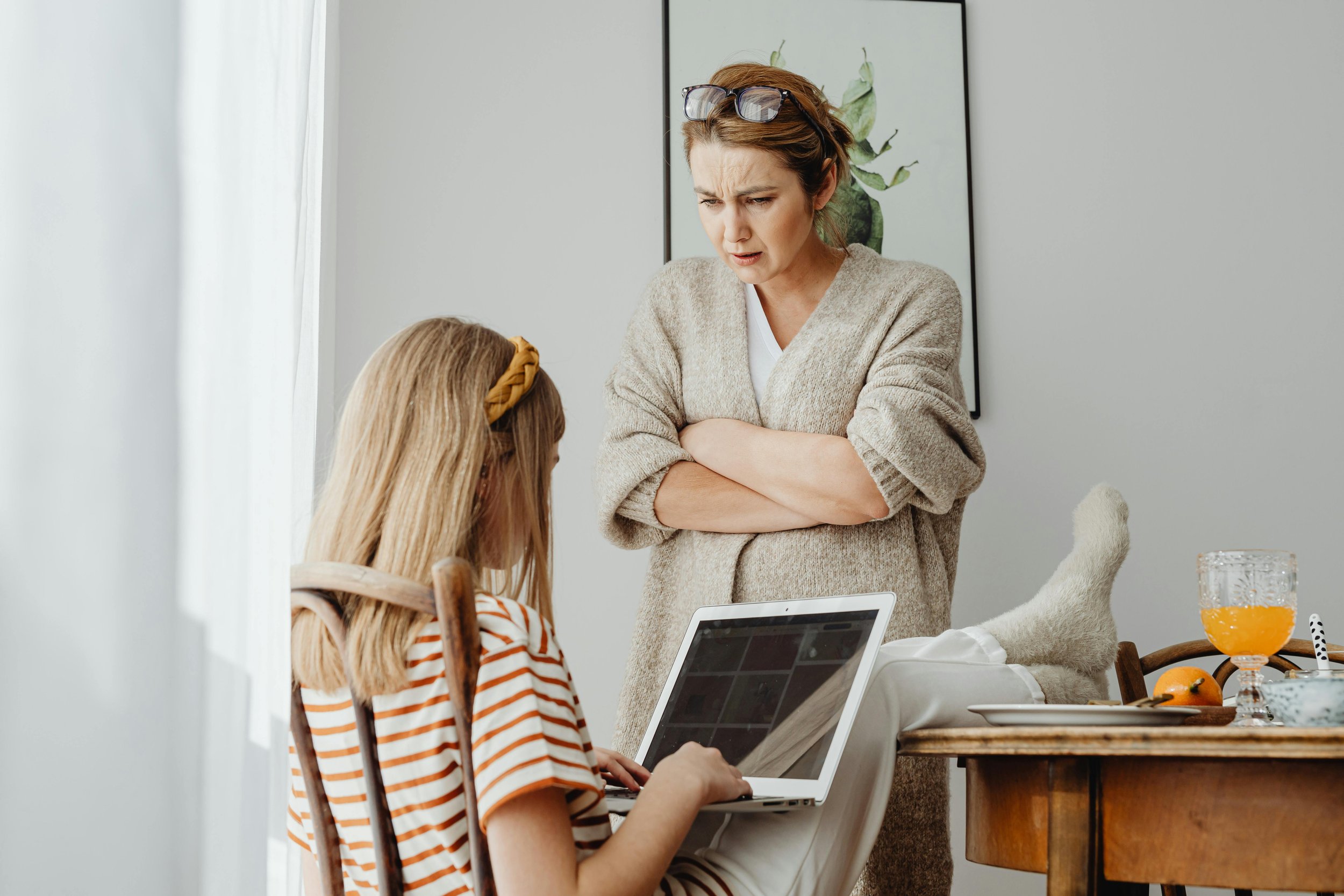 Mother correcting her daughter’s behavior during a serious conversation at the kitchen table.