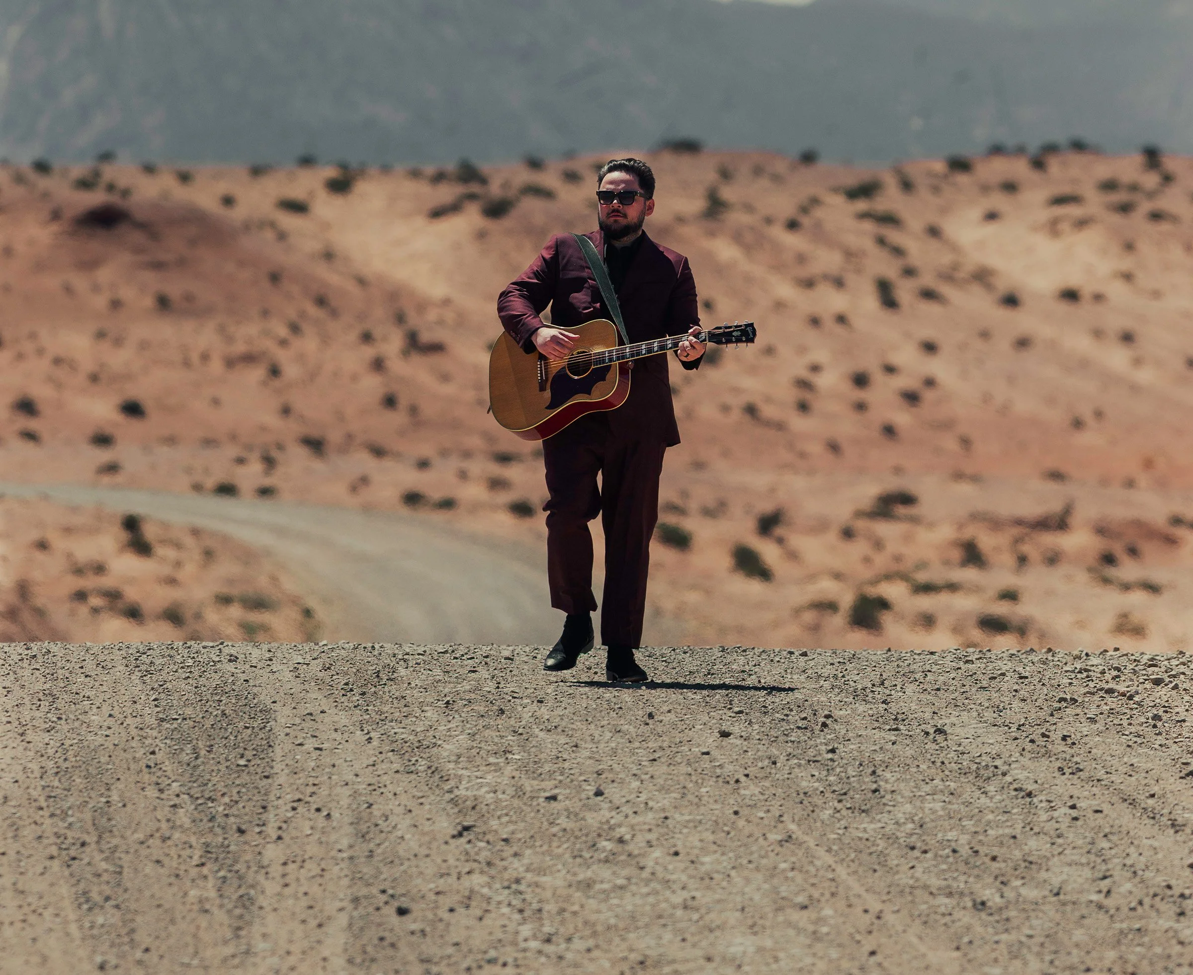 Wyatt Lowe playing guitar in desert