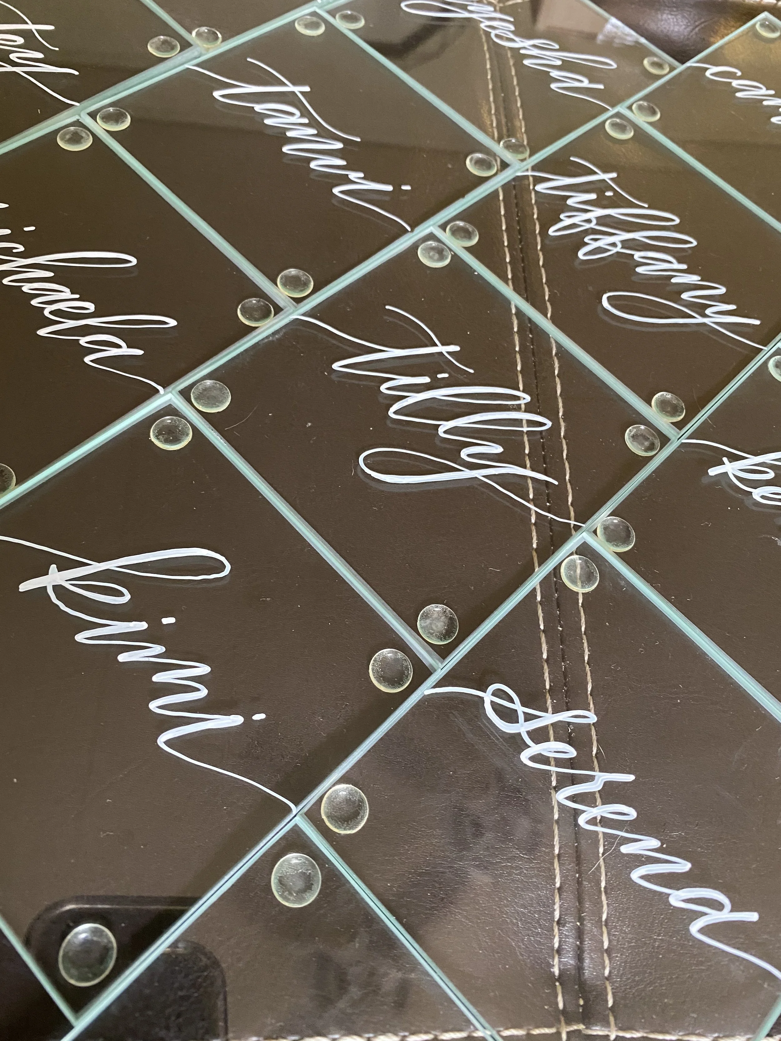 Glass coasters written with various names of women for a bachelorette party.