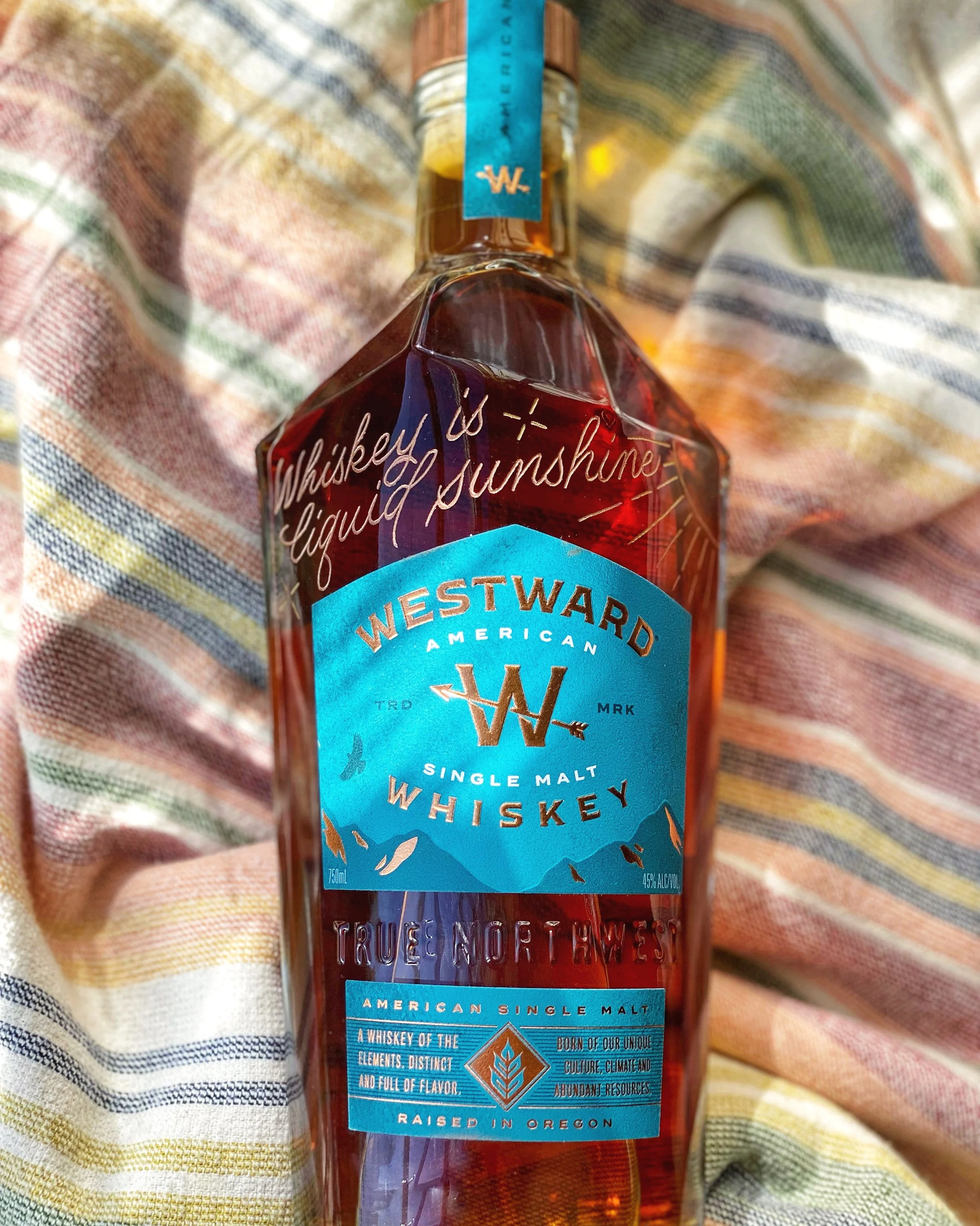 Westward Whiskey bottle engraved with a quote "Whiskey is liquid sunshine."