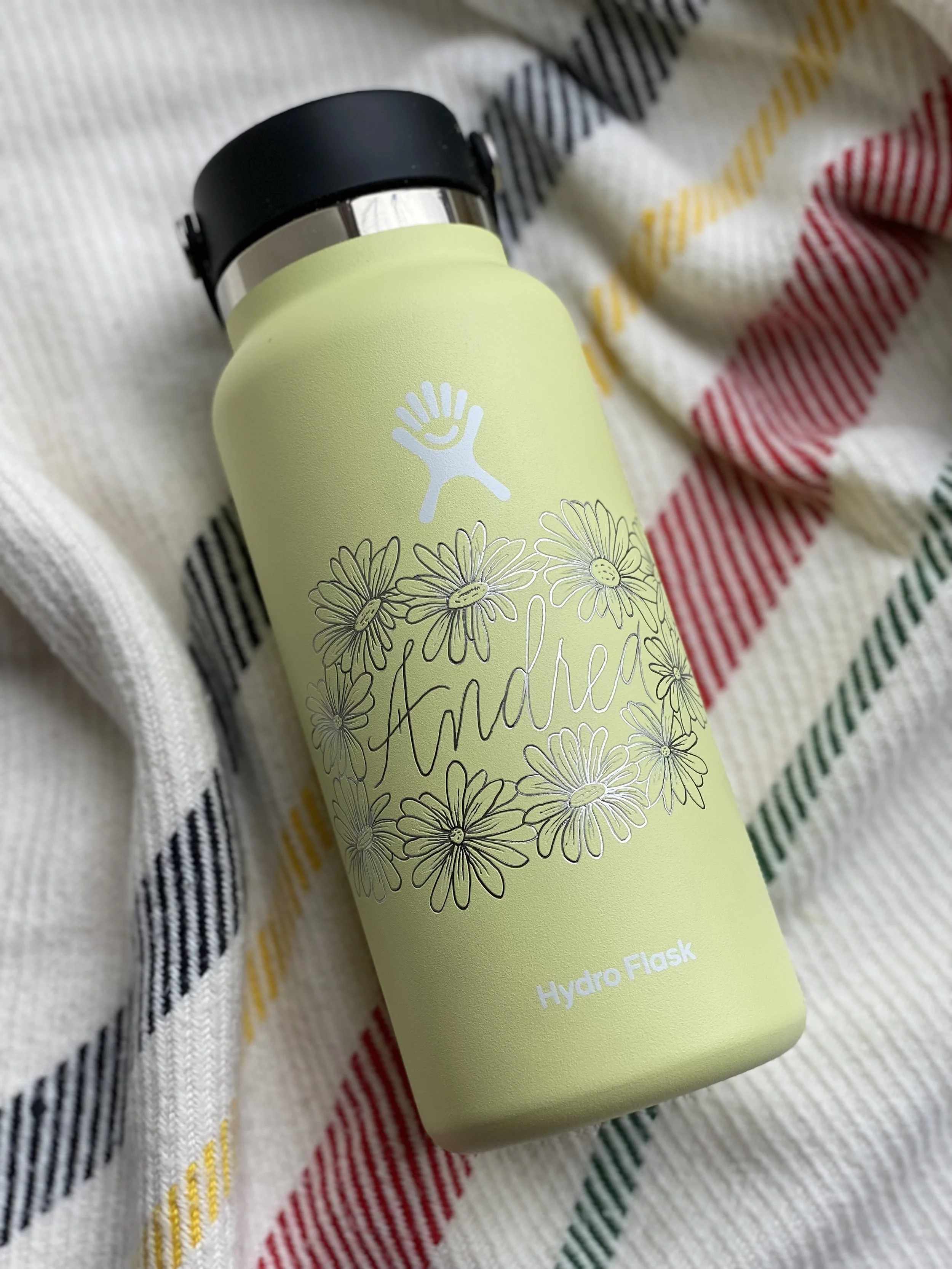 Engraved Hydro Flask yellow bottle with the name Andrea surrounded by daisies.
