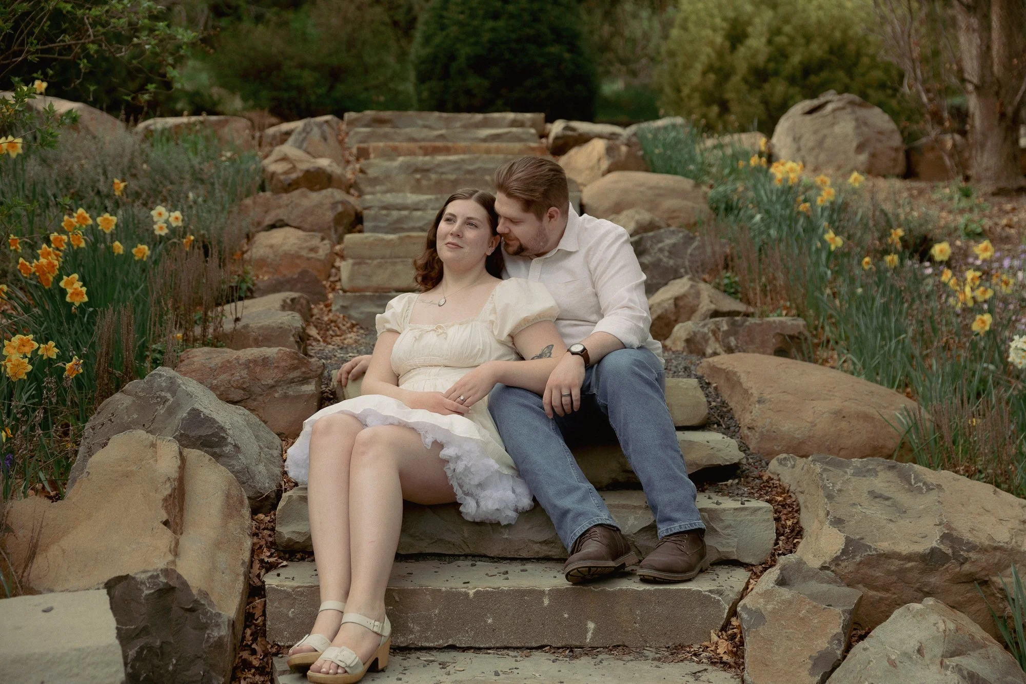 Couple sitting on stone steps surrounded by daffodils