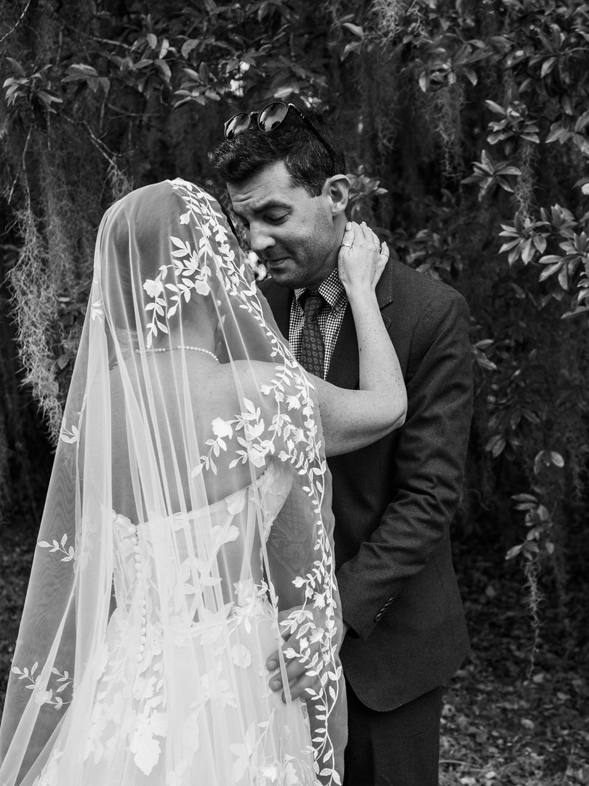 Couple embracing with a long lace veil flowing moments after their ceremony