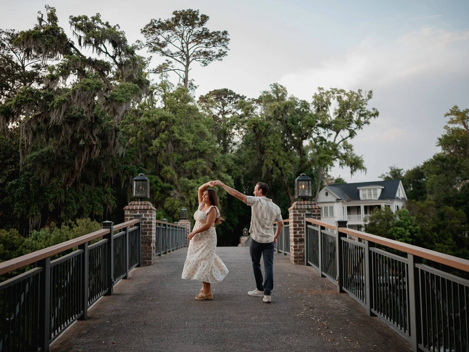 Couple walking along a footbridge over a marsh, holding hands and smiling toward each other.