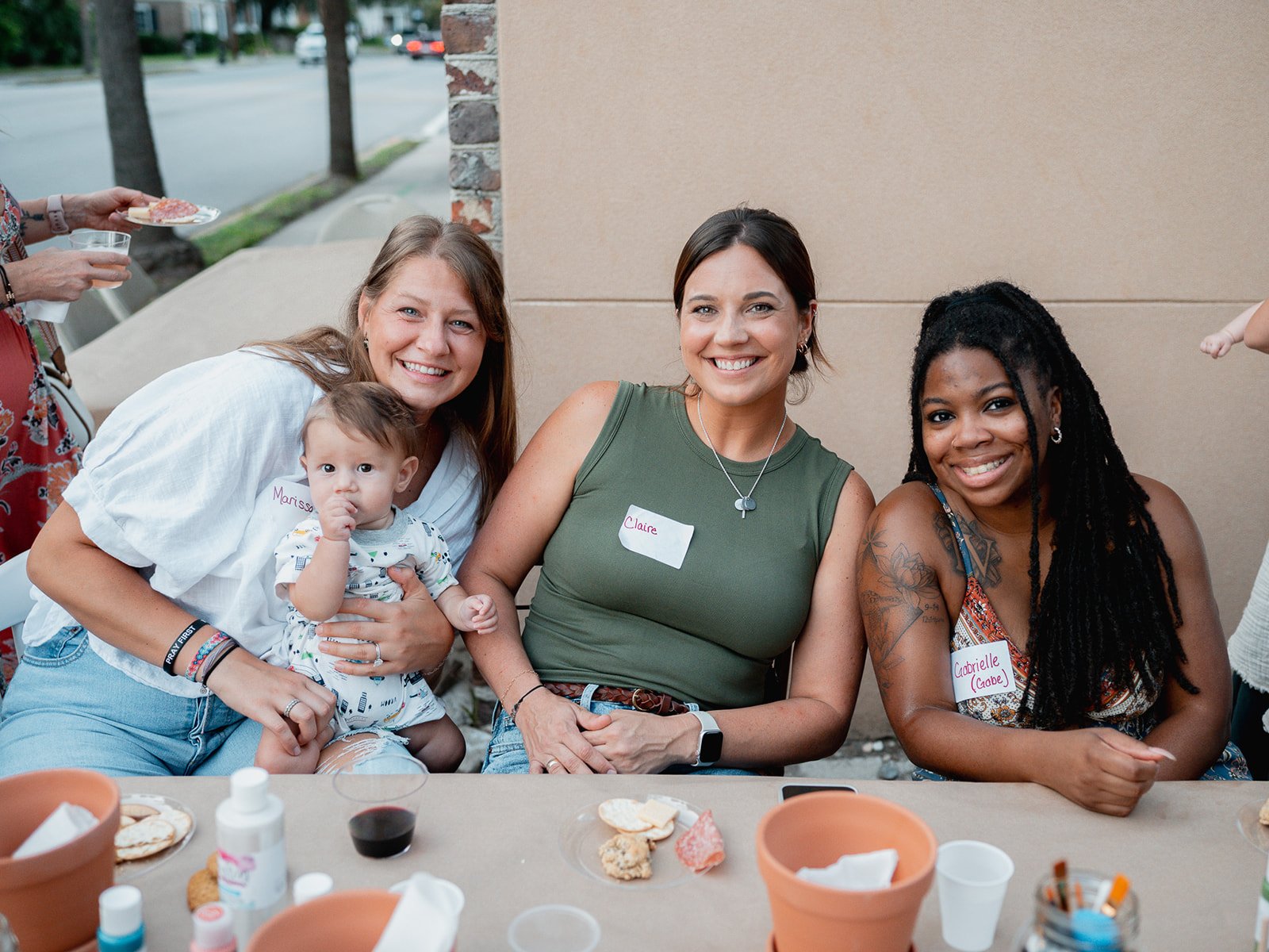 Mothers and babies gathered around a table with crafts and snacks during a baby shower.v