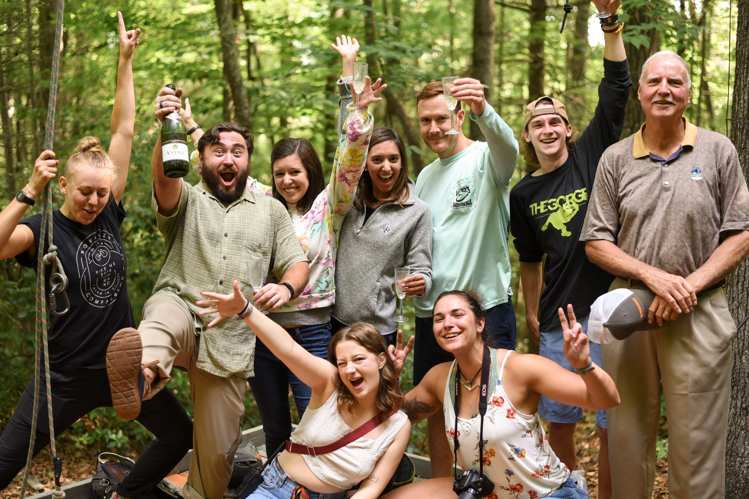 Group of friends raising drinks and cheering outdoors at a festive outdoor gathering.