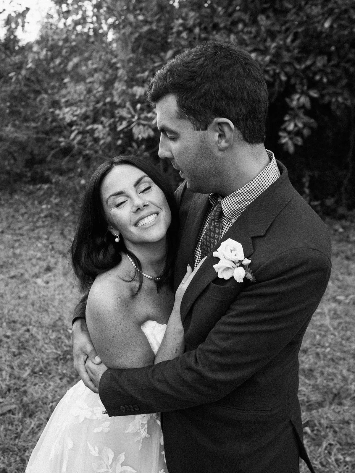 Close‑up of bride and groom hugging; she rests her head on his chest, eyes closed.