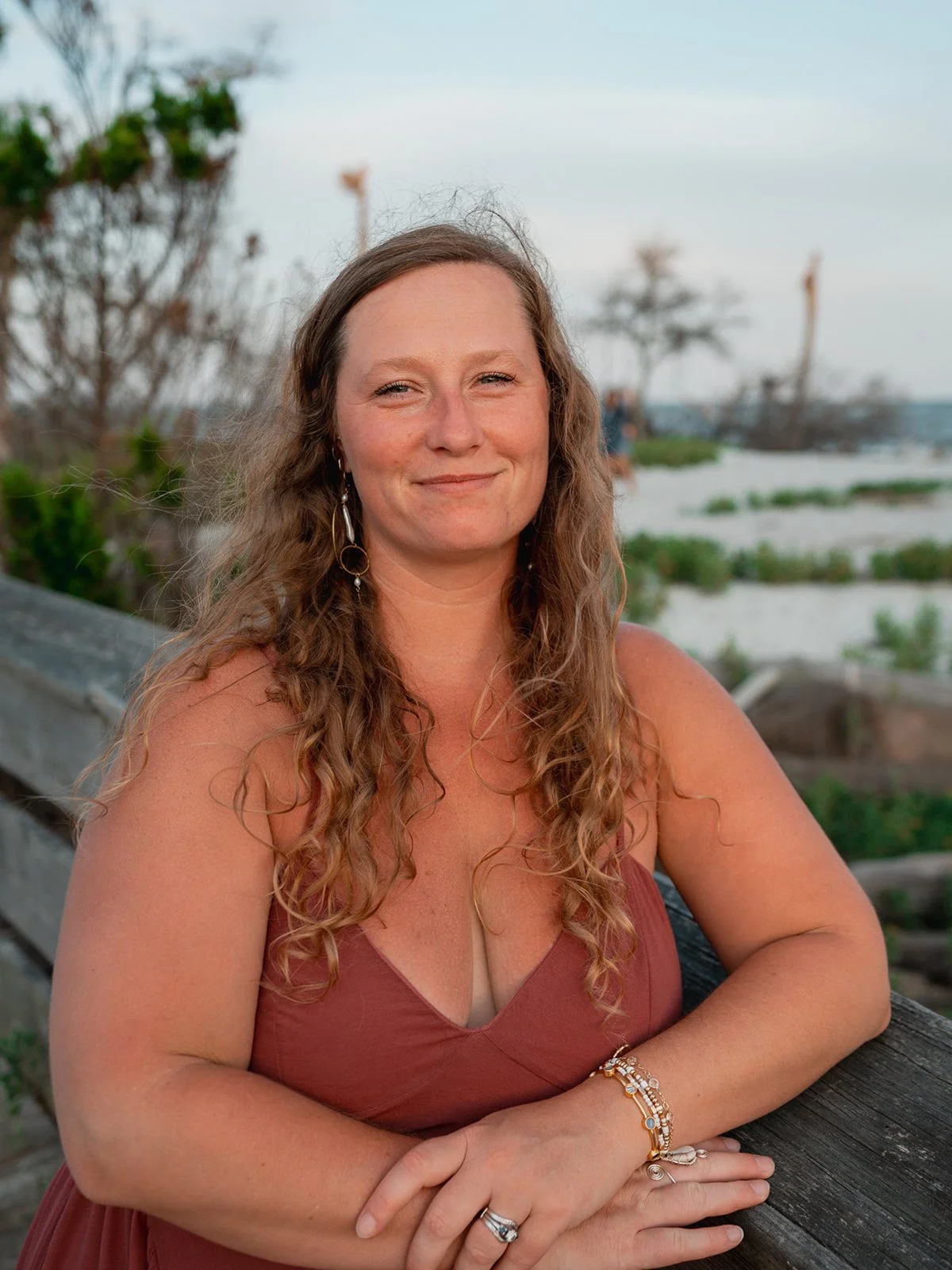 Woman leaning against a railing with long hair cascading over her shoulders, looking off into the distance.